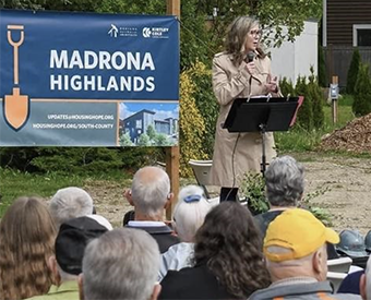 Woman speaking outdoors in front of a crowd at a HMF event